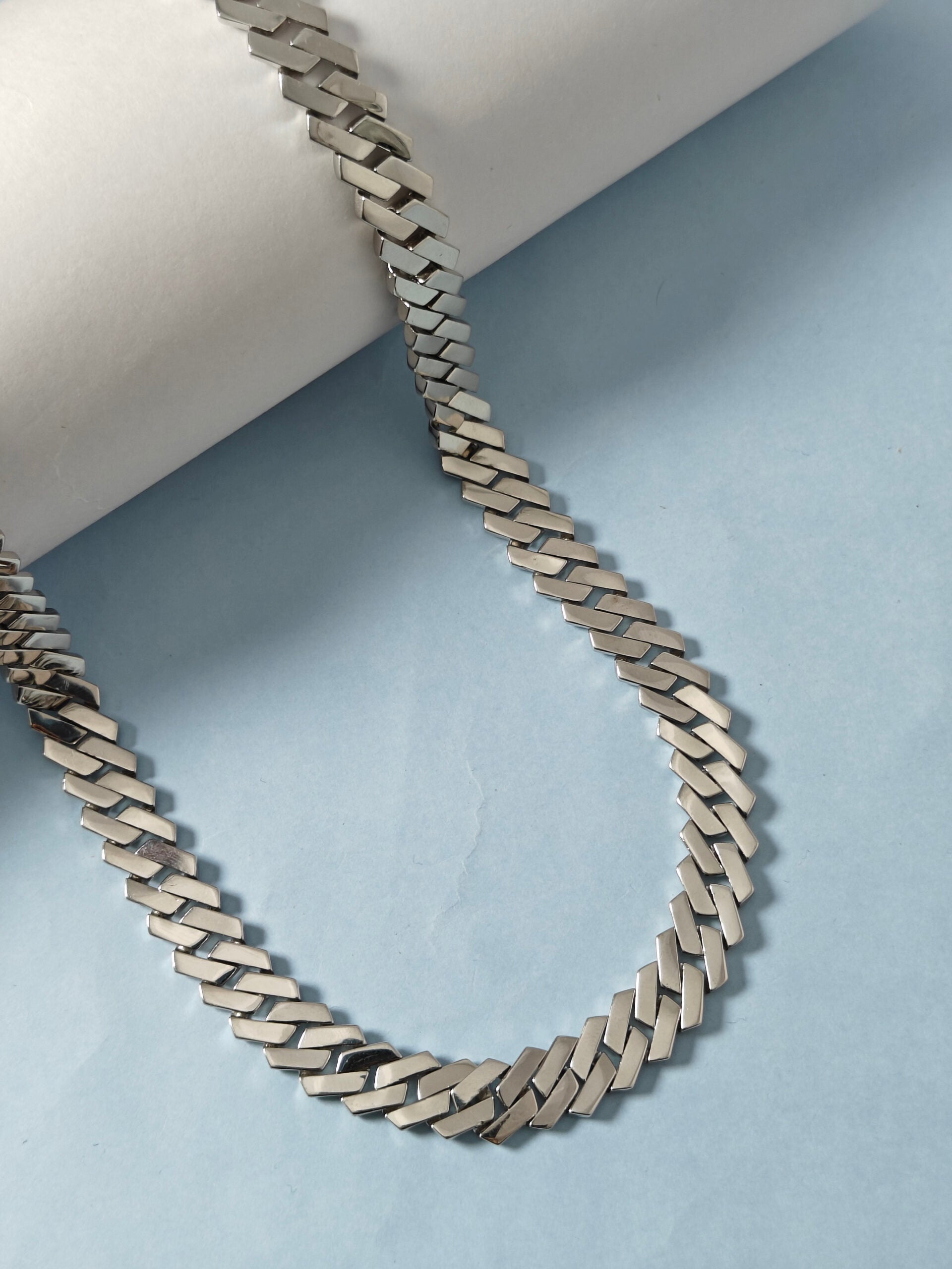Silver chain necklace on a light blue background